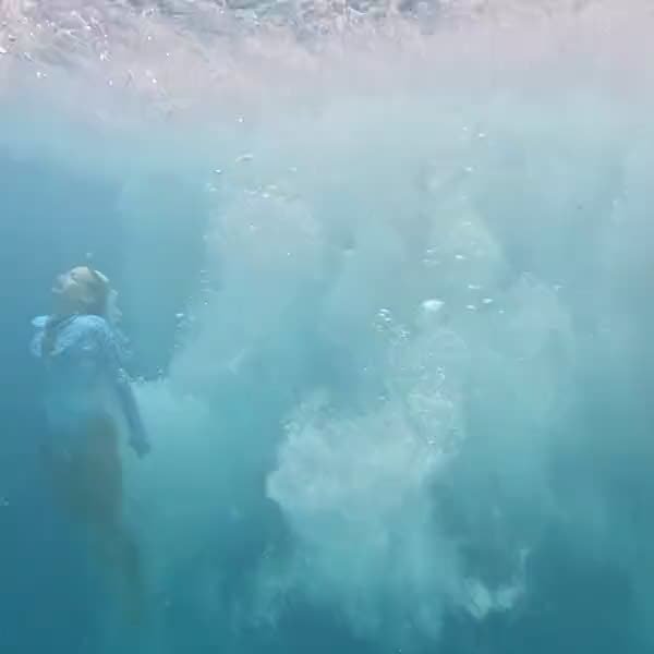 Underwater view of someone dropping into the sea in a cloud of bubbles