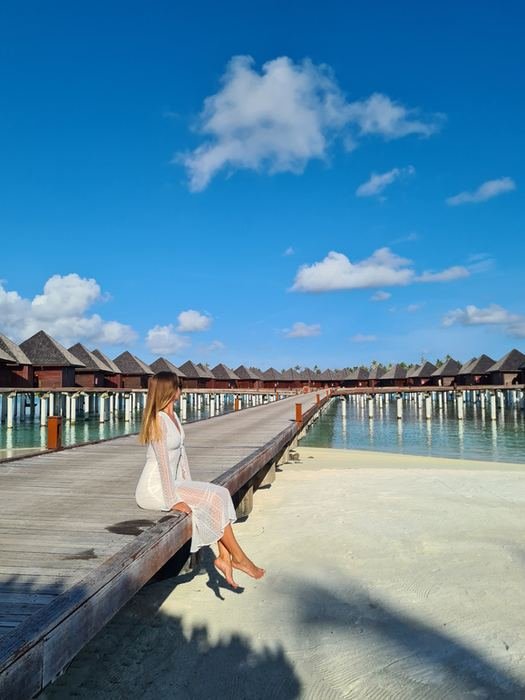 Woman sitting on a jetty next to overwater villas