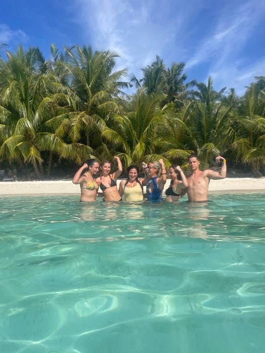 The group cheering in turquoise shallows in front of palms